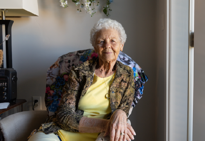 A woman sitting in a chair in front of a window.
