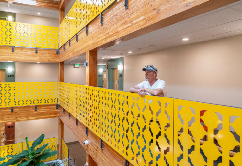 A man standing at a yellow railing at Mason Place