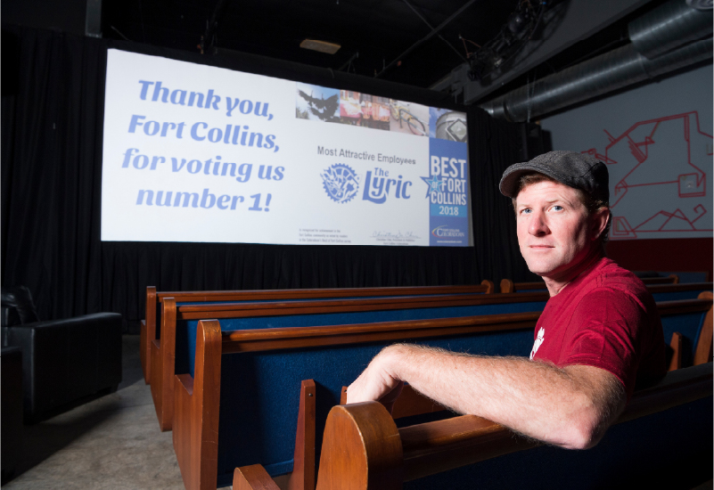 A person in a movie theater seat turned around with a movie screen behind them