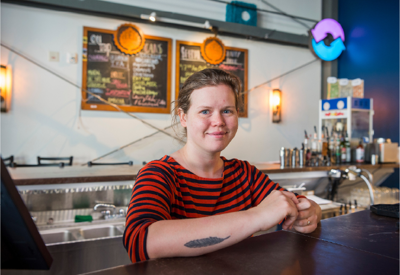 A woman smiling while standing behind a service counter