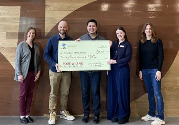 Five people standing in front of a wood wall holding a check made out to Food Bank of the Rockies