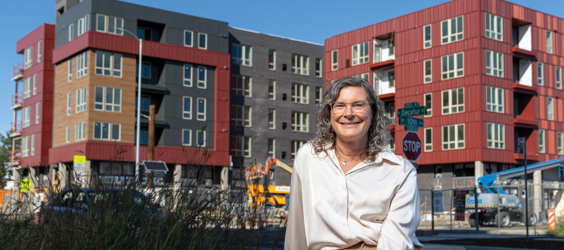Jennie Rodgers sitting in front of a multifamily building.