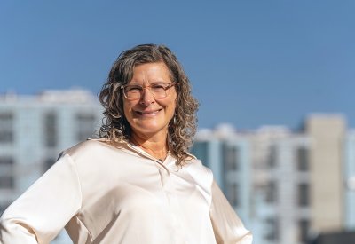 Jennie Rodgers smiling while standing in front of a large building