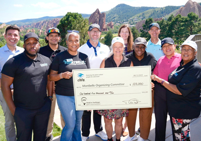 A large group of people on a golf course holding a large check.